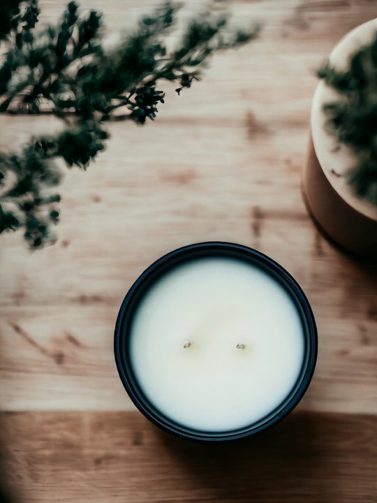 White candle in black jar on wood table